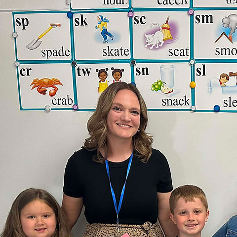 Brandi Filer smiling with students in a classroom